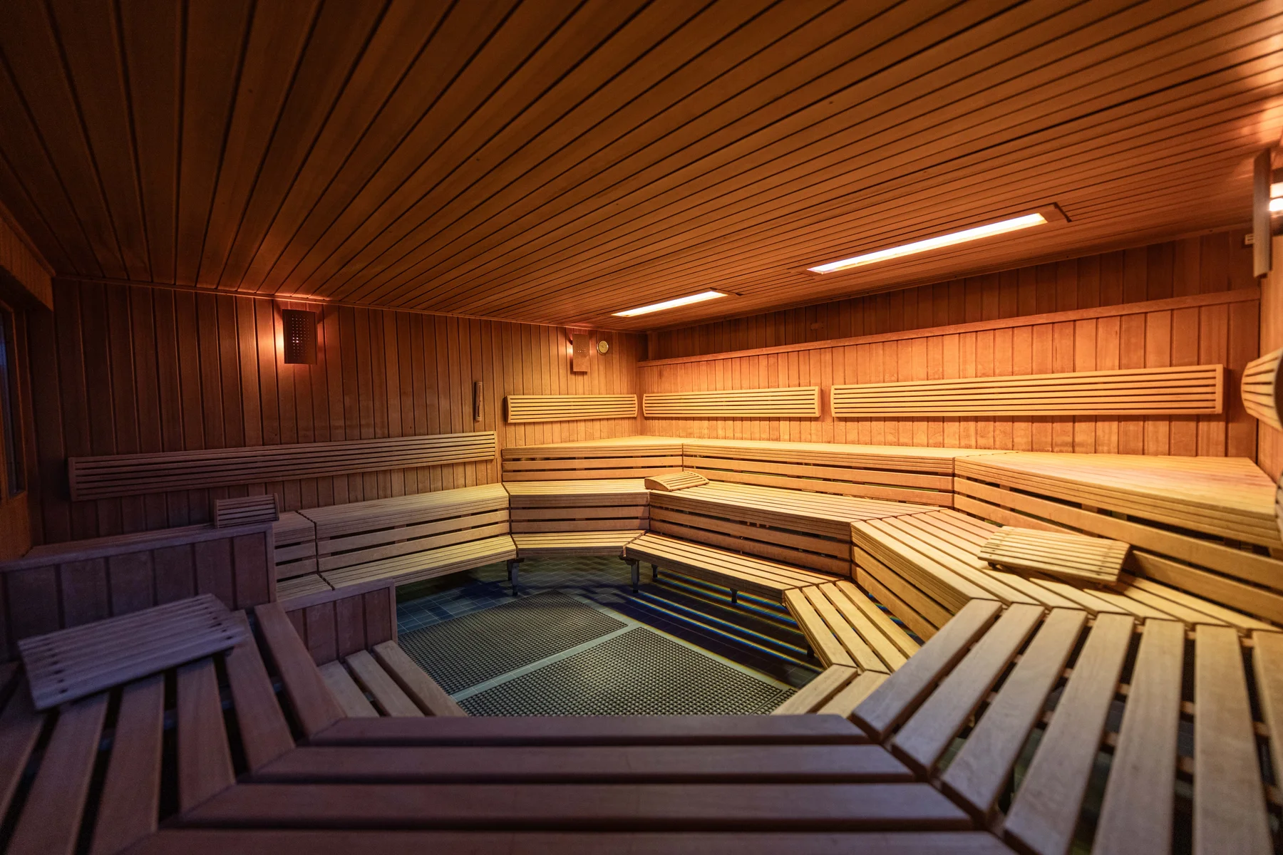 Holzbänke und warme Beleuchtung in der almiNa Sauna